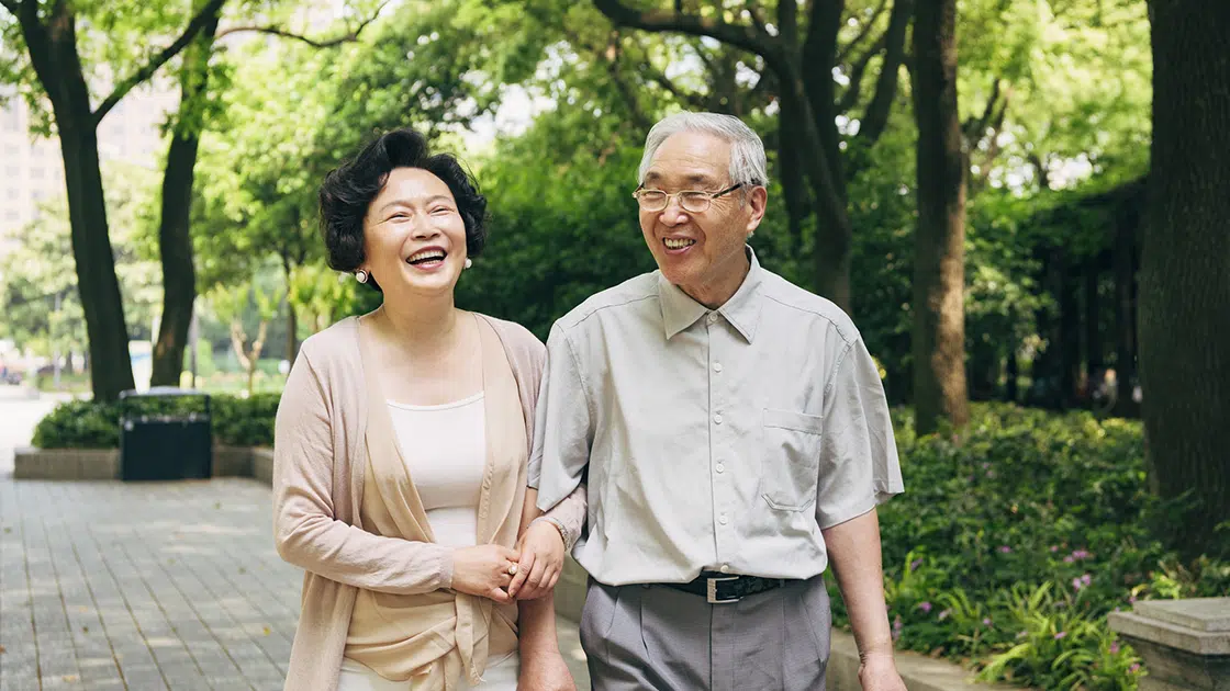 mature couple walking through park and smiling